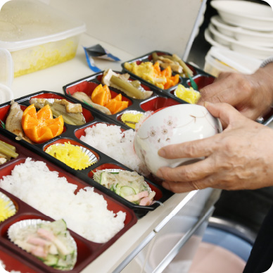 介護施設での食事配膳風景。職員が入居者向けの弁当を準備している
