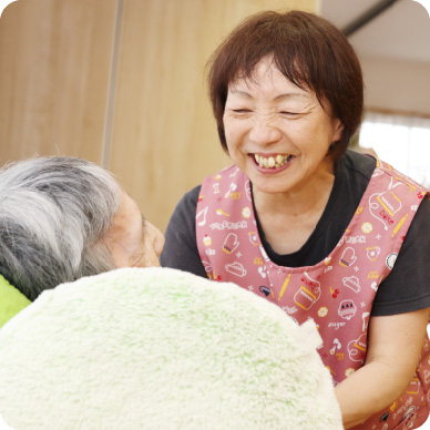 介護職員と入居者が一緒に笑顔で過ごす様子。コミュニケーションと信頼関係を示す温かい一場面。